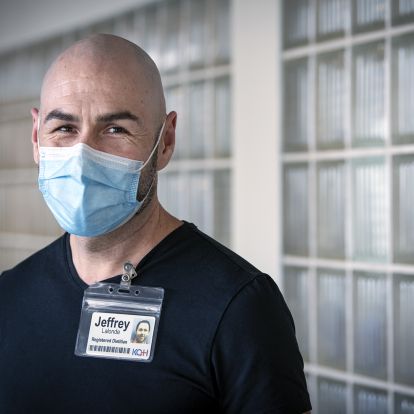 Jeffrey Lalonde is pictured in a hallway at the KGH site. He has dark brown eyes and is bald. He’s wearing a navy blue, V-neck top.