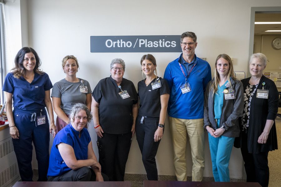 A group shot of Teri and her colleagues standing in a hallway in front of a sign that says “Ortho/Plastics.”