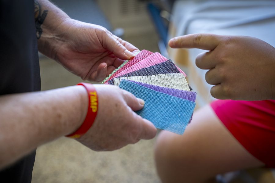 A close up shot of Teri’s hands, holding cast colour options, while a young patient points to the colour he wants.